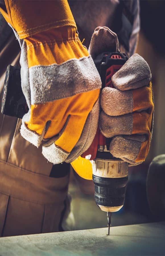 Construction Worker Using A Drill — H&D Building Supplies in Heatherbrae, NSW