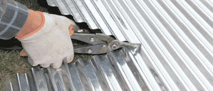 Handyman Cutting Corrugated Iron With Cutters — H&D Building Supplies in Heatherbrae, NSW