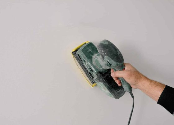Repairman Polishing Wall With Construction Tool — H&D Building Supplies in Heatherbrae, NSW Repairman Polishing Wall With Construction Tool — H&D Building Supplies in Heatherbrae, NSW