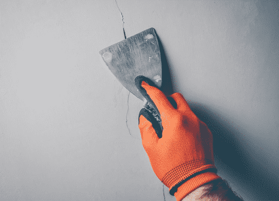 Worker Repairs Cracks On A Wall — H&D Building Supplies in Heatherbrae, NSW